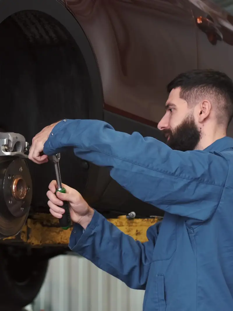 Mechanic replacing a brake caliper on a car raised on a lift